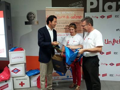 Responsables de la Comunidad de Madrid y Cruz Roja posando con los lotes de material escolar que han entregado