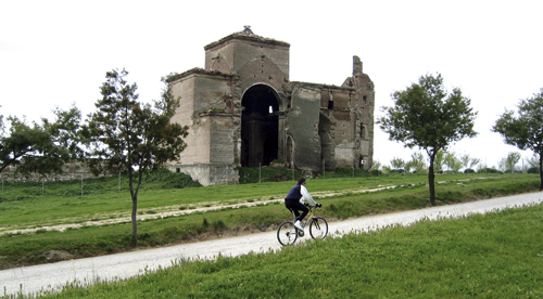 Ciclista pasando por delante de una ermita recorriendo una Ruta Verde